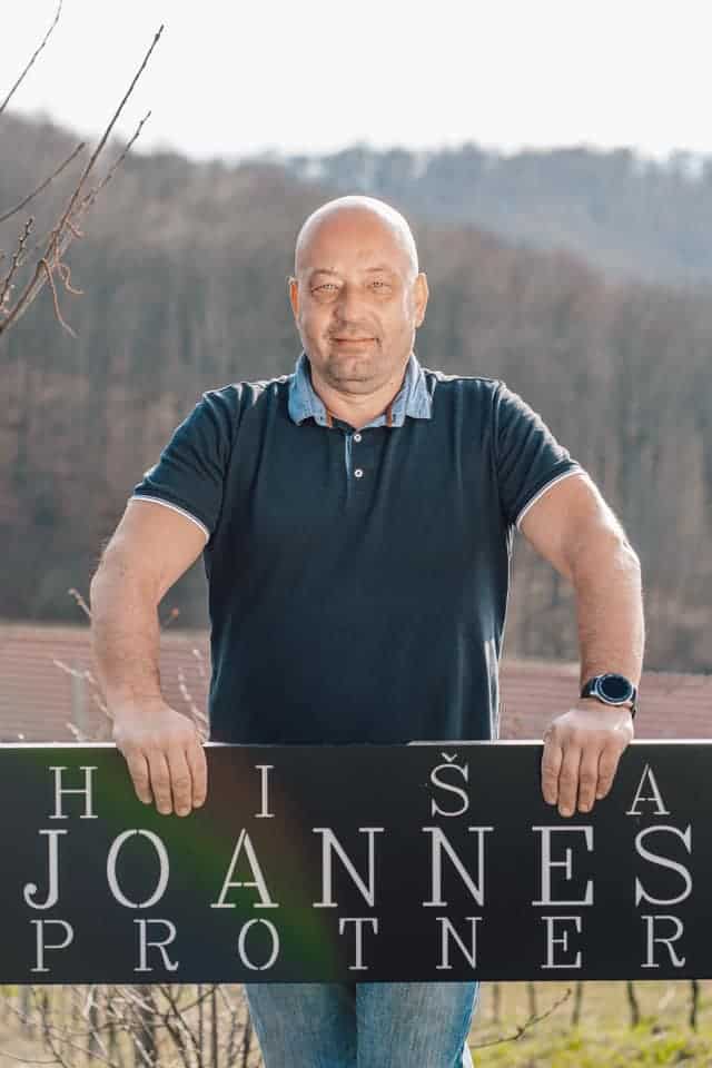 Portrait of a man outdoors with vineyard background, promoting Hiša Joannes Protner wines.